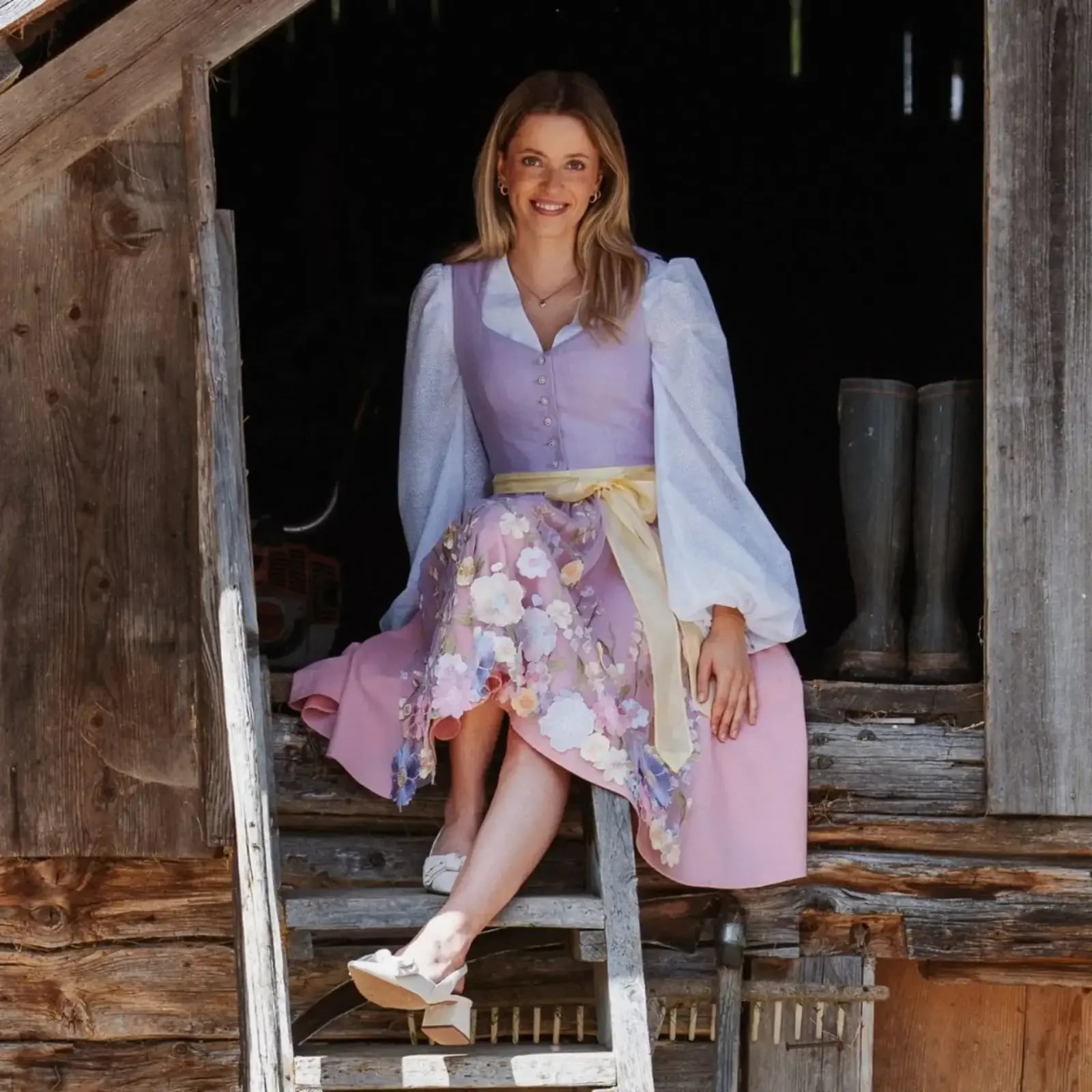 Julia Kugi im selbst geschneiderten Dirndl vor einer Holzhütte